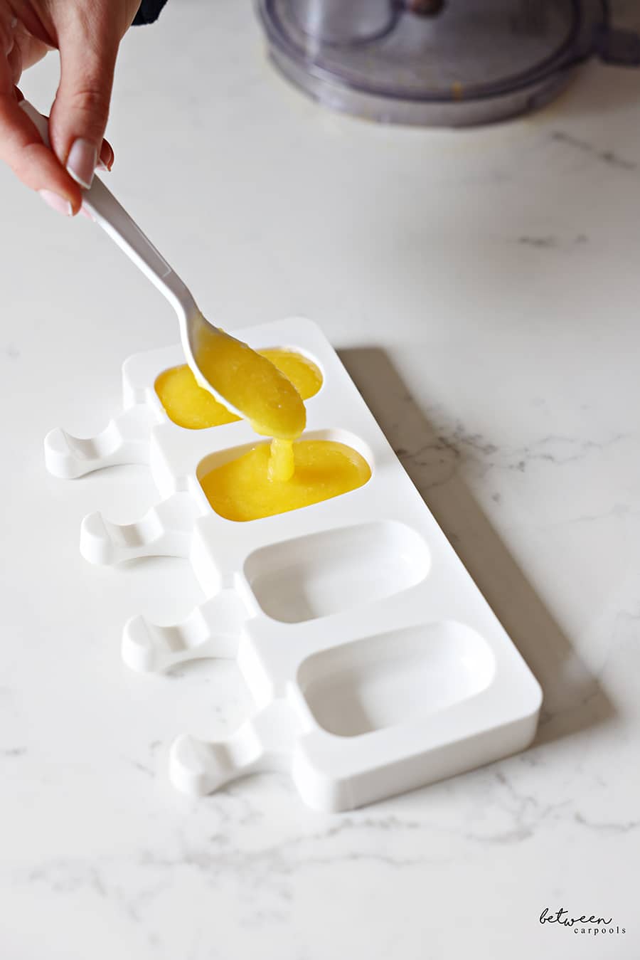 spooning mango sorbet into molds