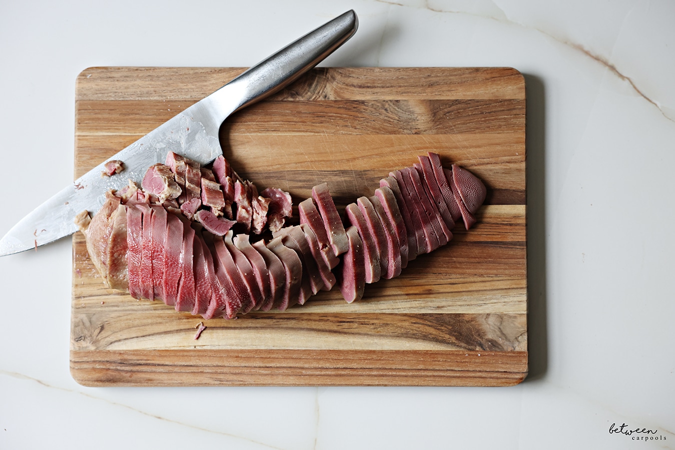 sliced cooked tongue on a cutting board with a knife