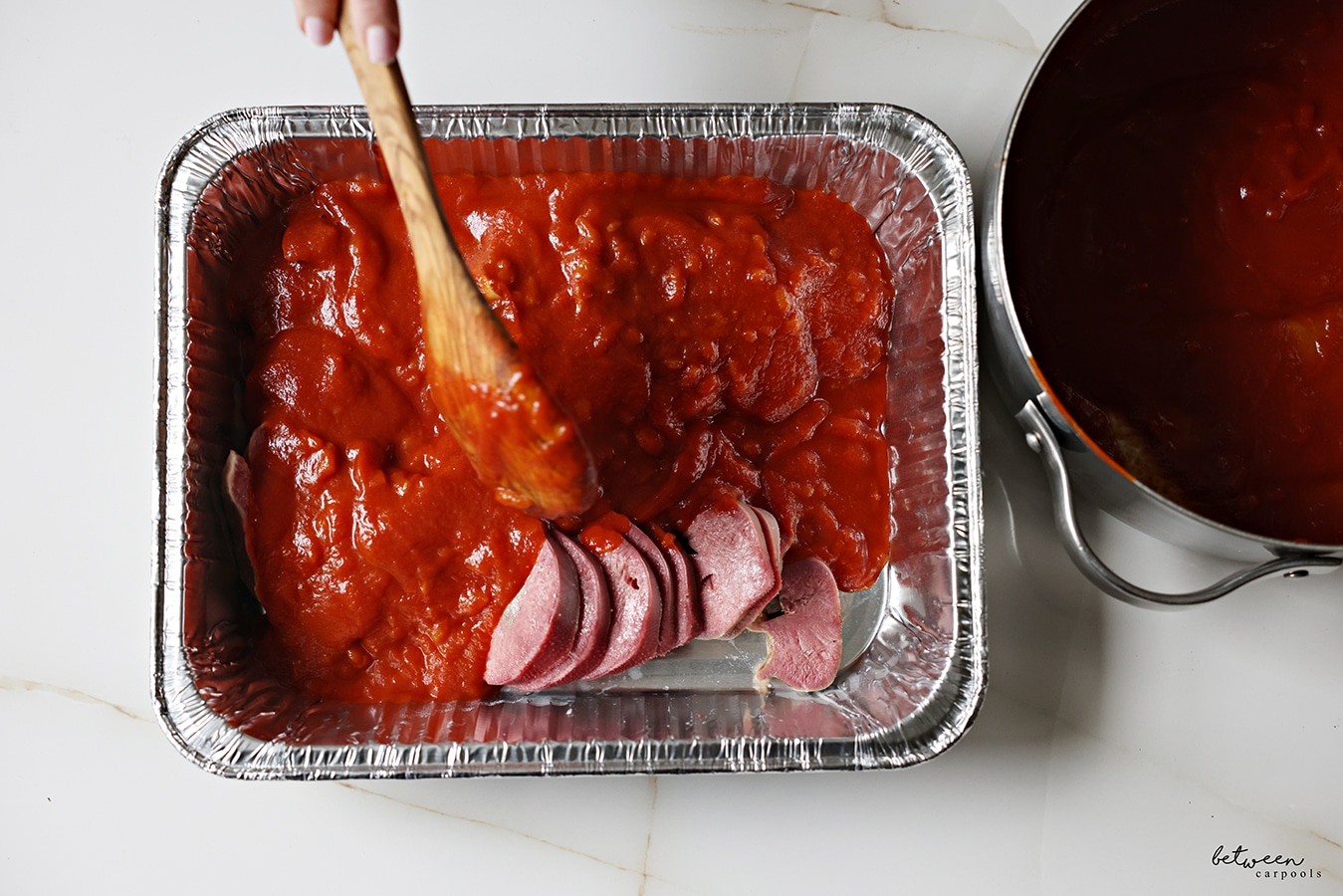 sliced cooked tongue in a pan with sauce over it