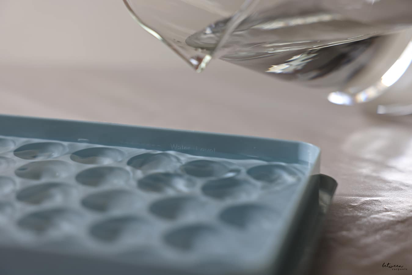 pouring water from a pitcher into the ice tray