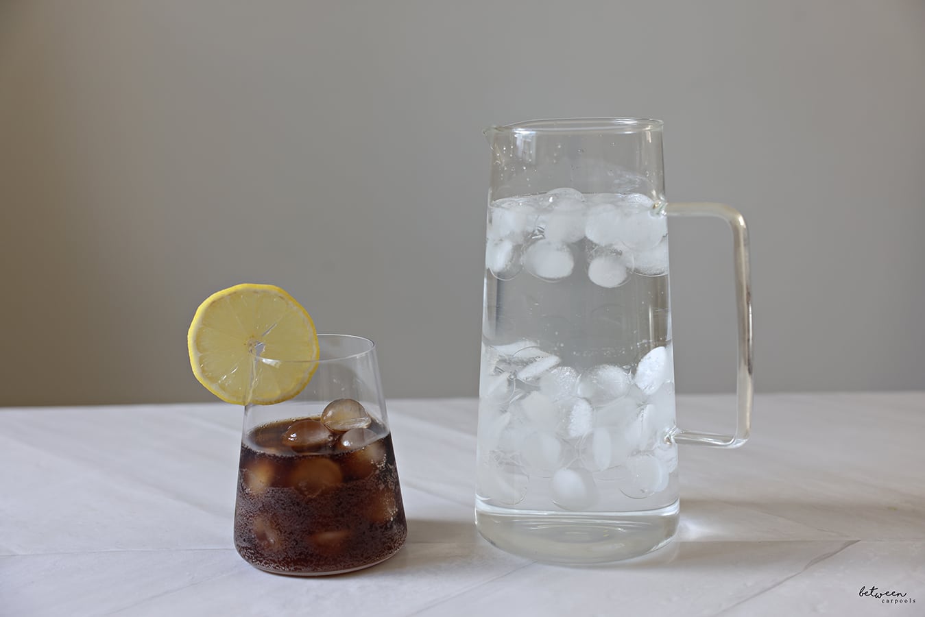 Drinks with frozen Ice Balls - water in a pitcher and soda in a glass with a sliced lemon