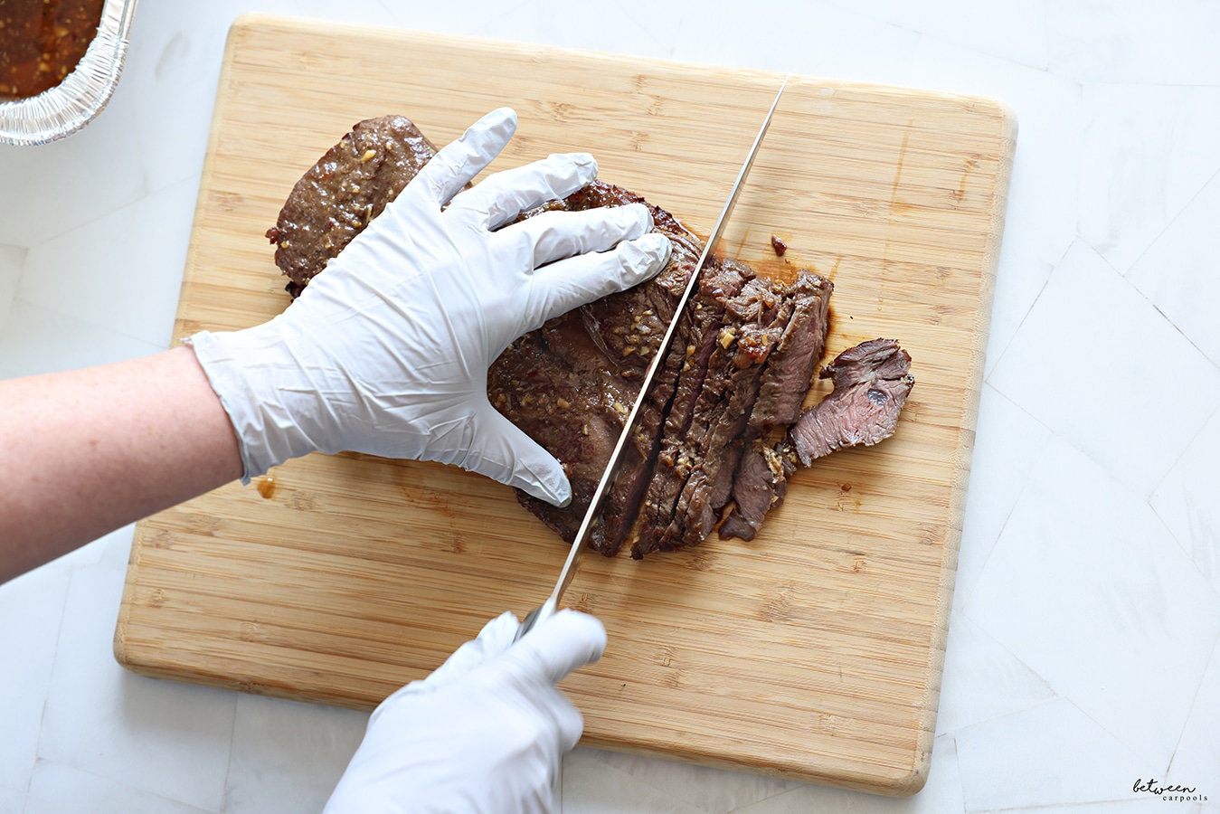 slicing London broil on a wooden cutting board