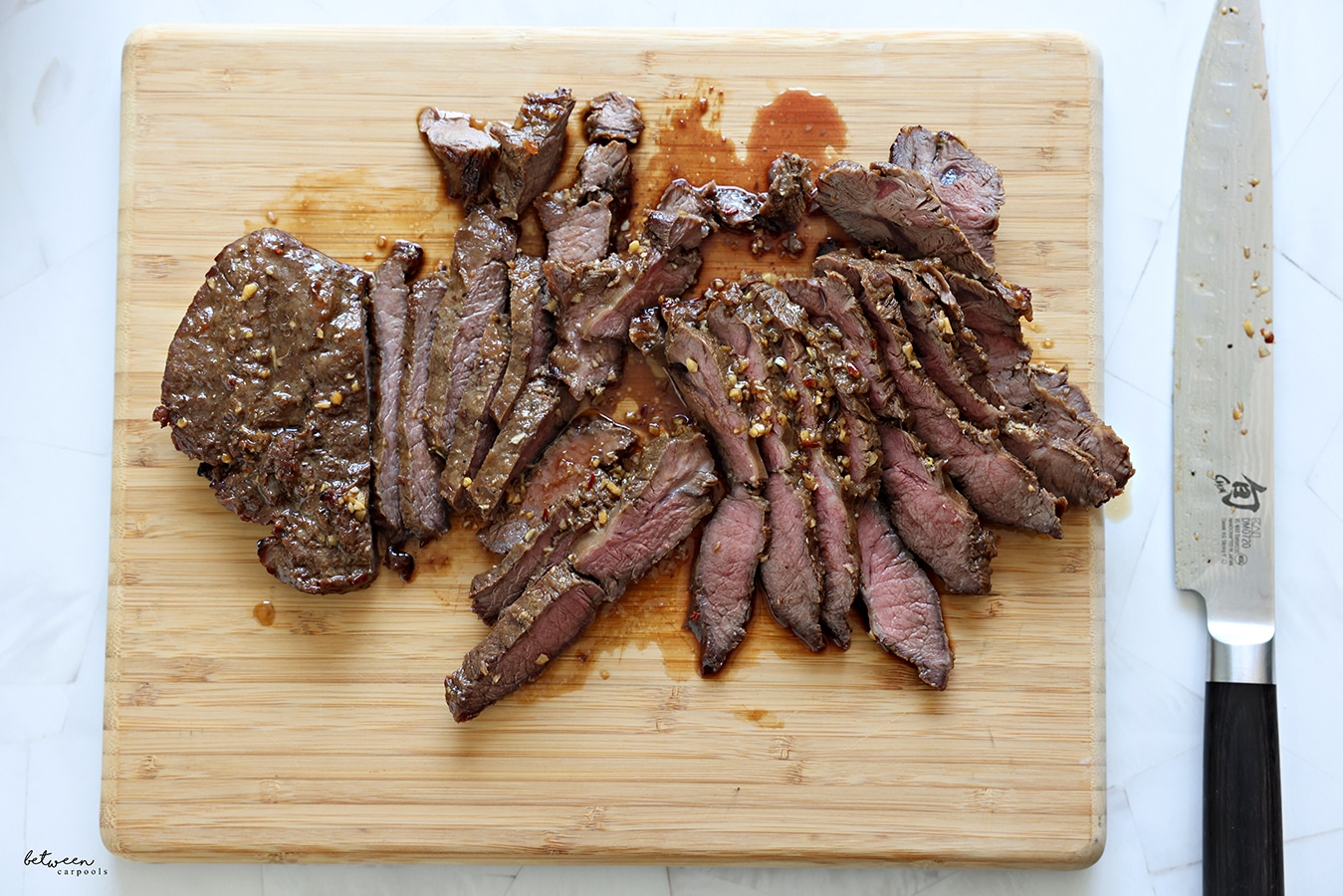 sliced London broil on a wooden cutting board