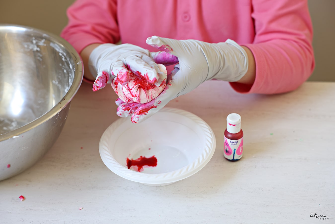 Mixing (with gloved hands) some homemade Play-Doh with red food coloring