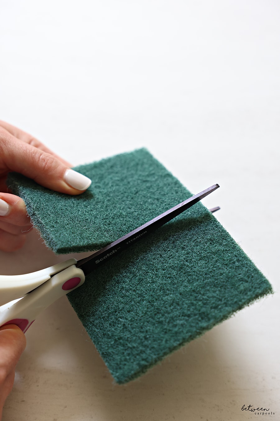 cutting a Scotch-Brite Heavy Duty Scour Pad in half