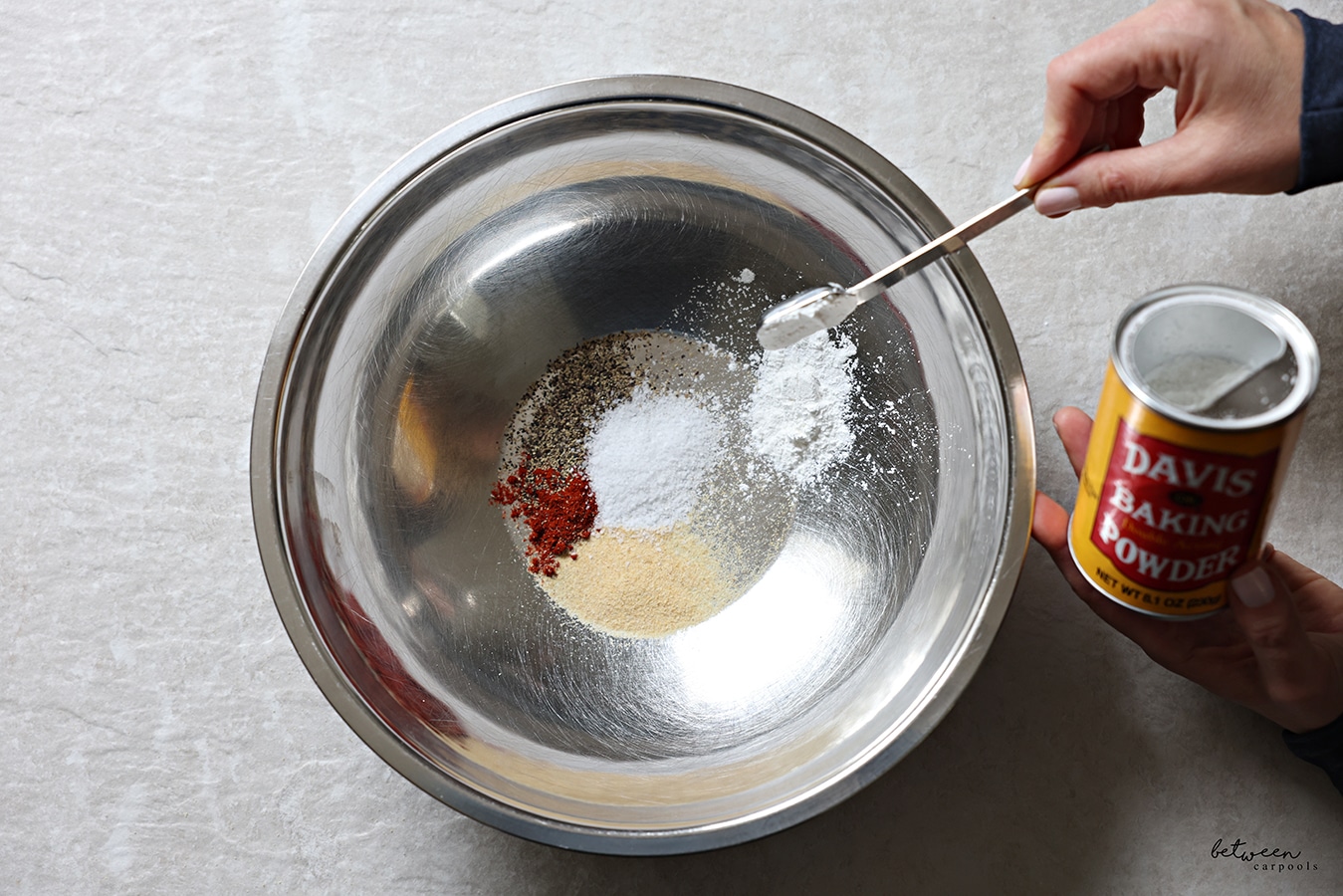 Adding all dry ingredients to a metal mixing bowl