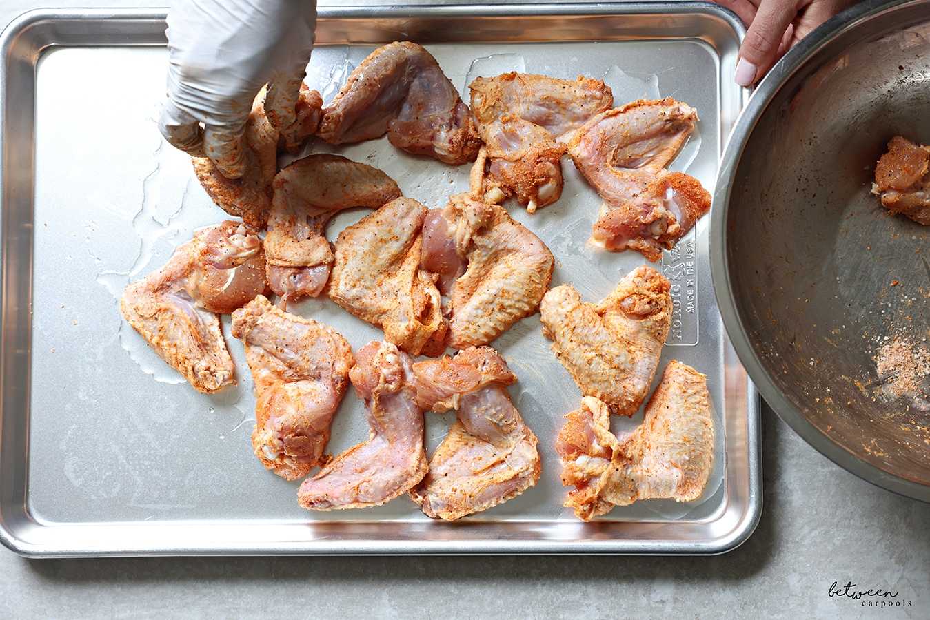Placing the wings mixed with dry ingredients on a generously greased sheet pan.