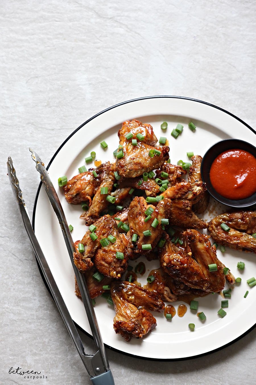 Wings, plated - topped with scallions - and hot sauce