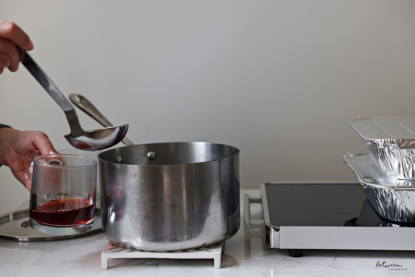 Serving with a ladle from a pot on a trivet near a hot plate.