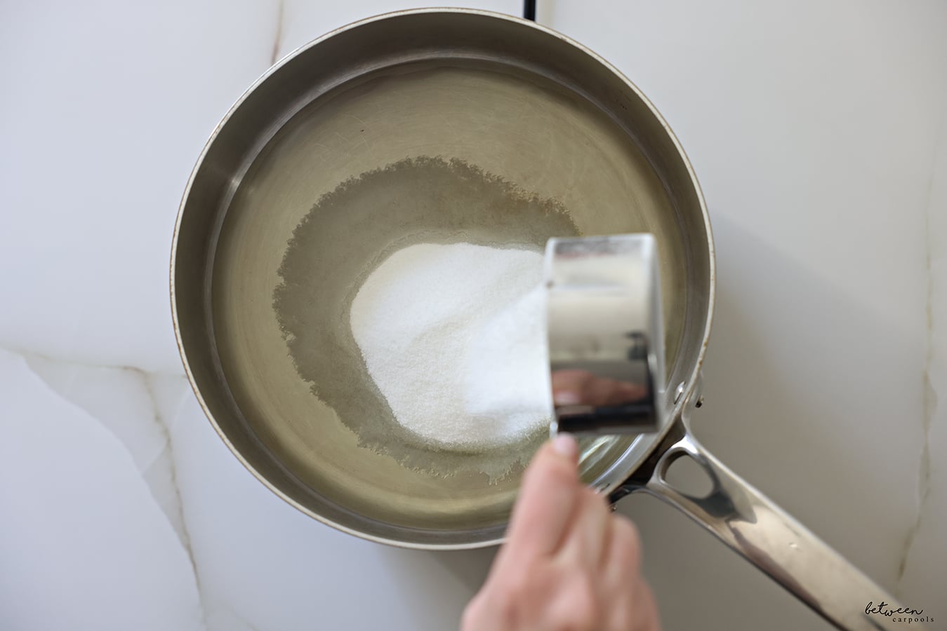 Adding sugar to a pot with oil.