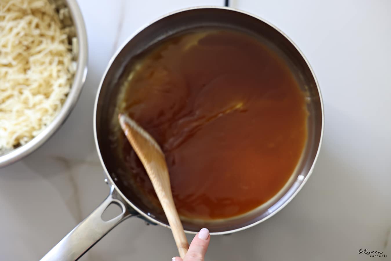 Mixing oil and sugar that became a deeply golden color - in a pot with a wooden spoon.