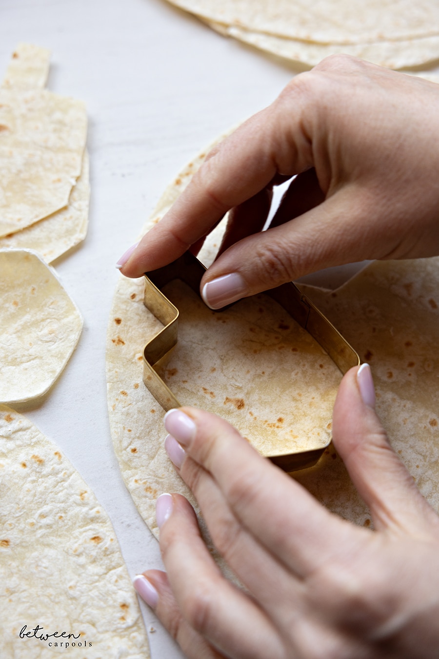 Using a dreidel cookie cutter to cut a dreidel shape out of wrap.