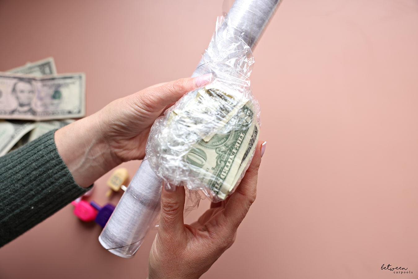 Holding the prize ball with a layer of money bills wrapped in Saran Wrap.