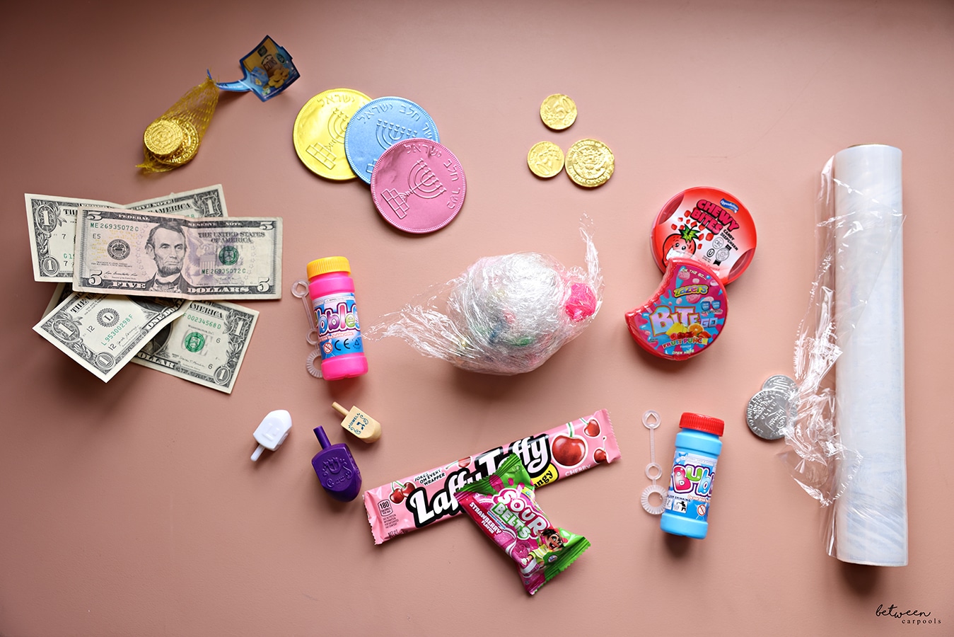 Small prizes, dreidels, candy, chocolate coins, money, and Saran Wrap.