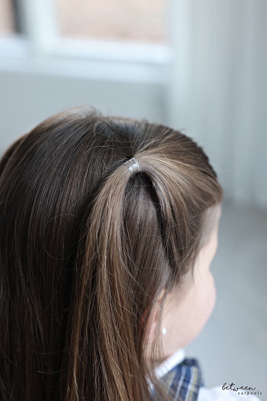 A little girl with clear ponytail holders in her hair.