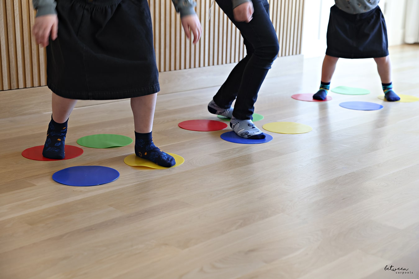 3 children dancing on vinyl circles. 4 circles - yellow, blue, green, and red - per child.