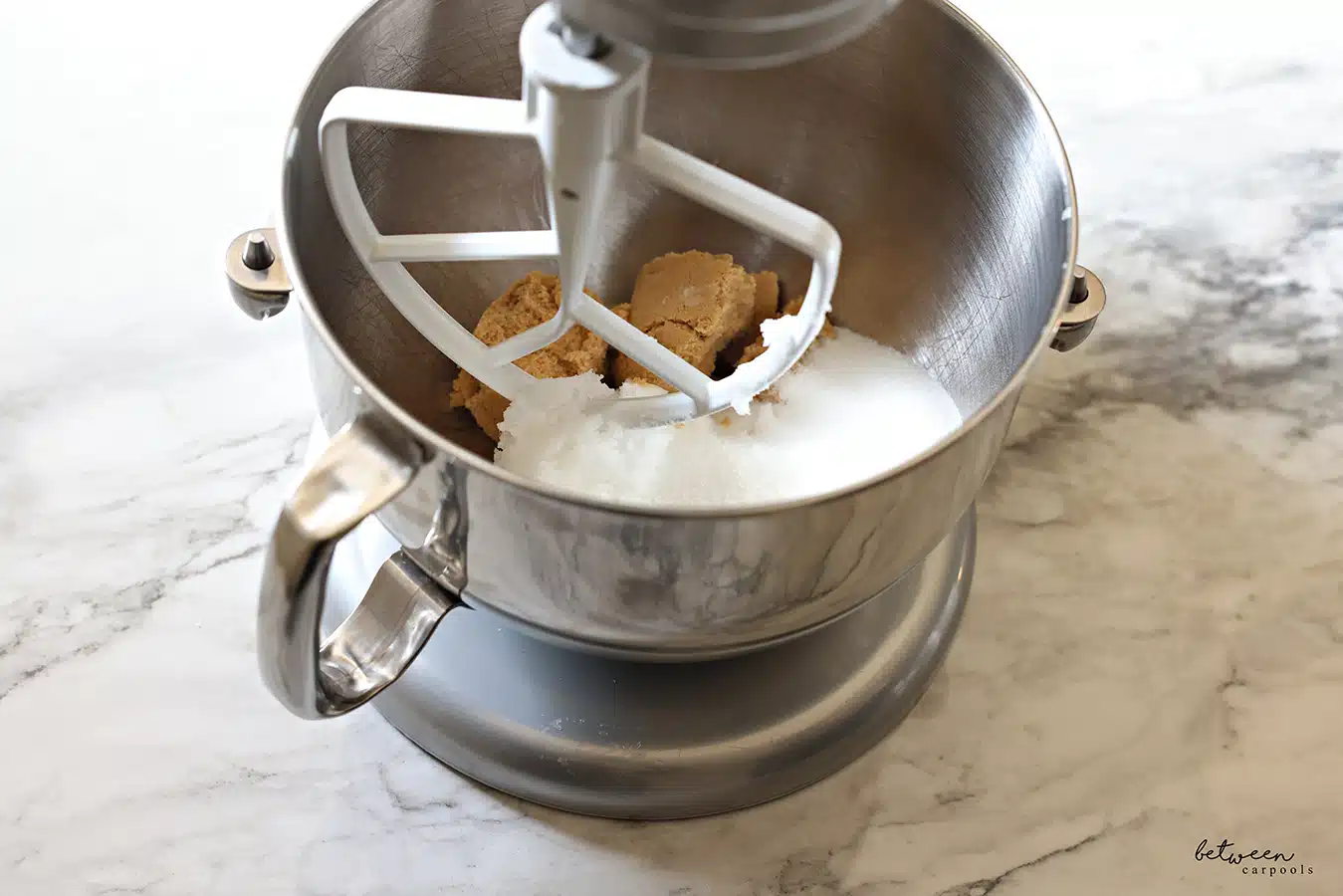 Sugars in the metal bowl of a Kitchen Aid mixer with the flat beater.