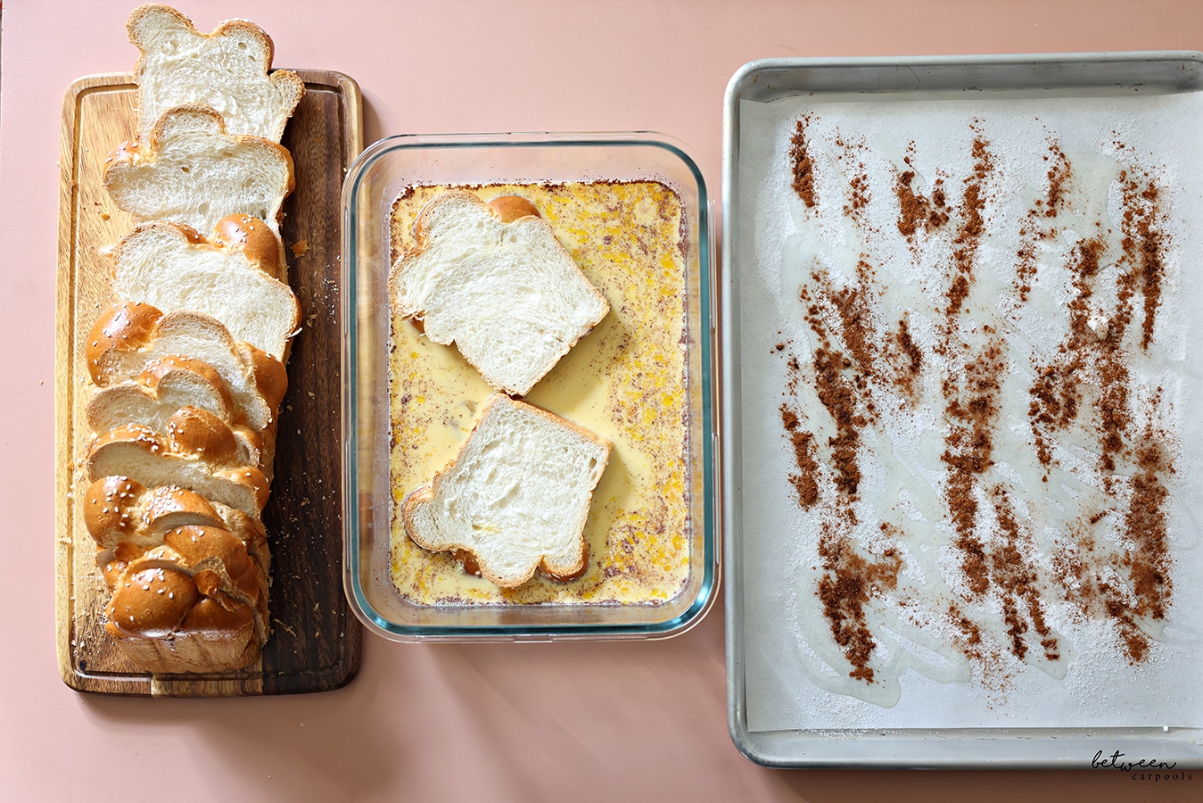 Sliced challah on a wooden board, 2 slices of challah in French toast batter in a glass dish, a parchment lined baking sheet drizzled with oil, sugar and cinnamon.