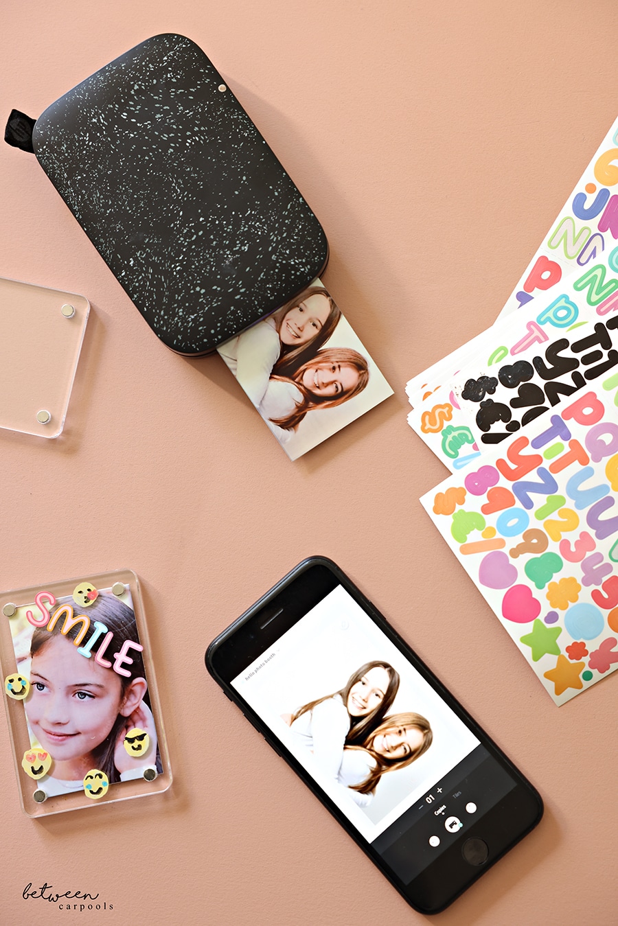 A decorated acrylic frame with a printed photo, an HP Sprocket Portable 2x3 Instant Color Photo Printer, an iPhone, and stickers.