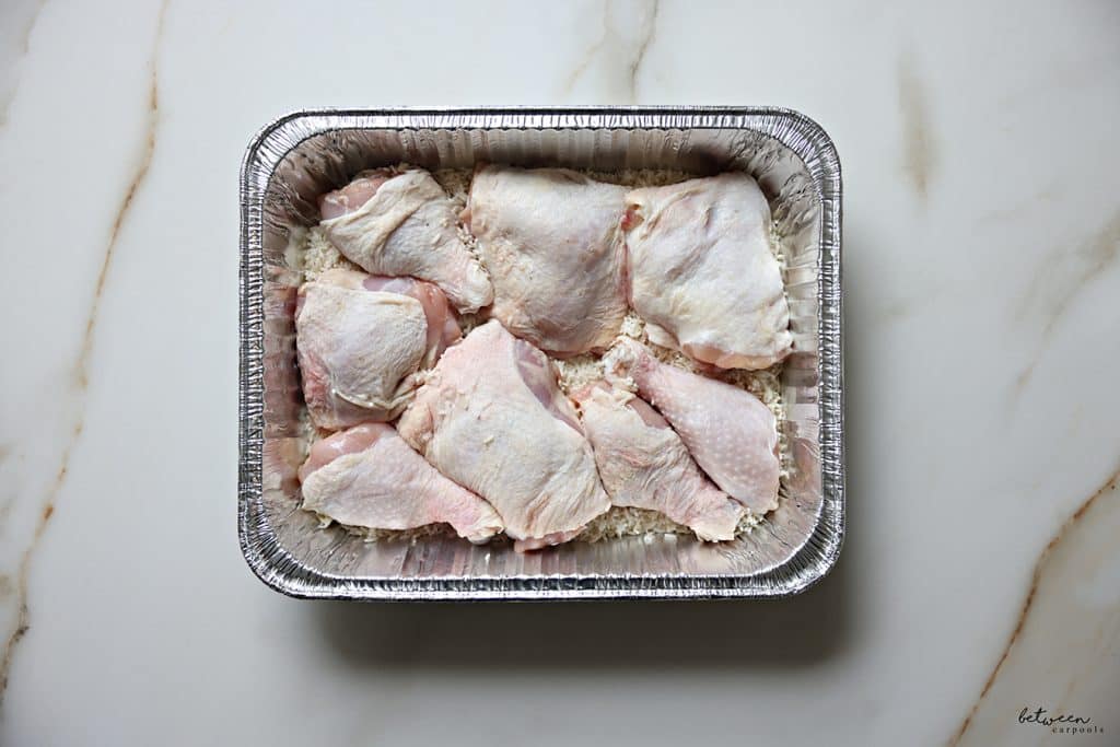 Chicken legs, cut in half, over rinsed raw rice in a 9x13 aluminum pan.