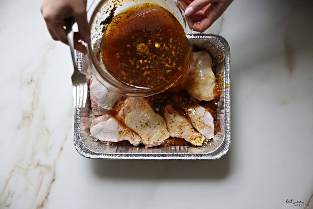 Pouring the sauce over chicken legs, cut in half, and rinsed raw rice in a 9x13 aluminum pan.