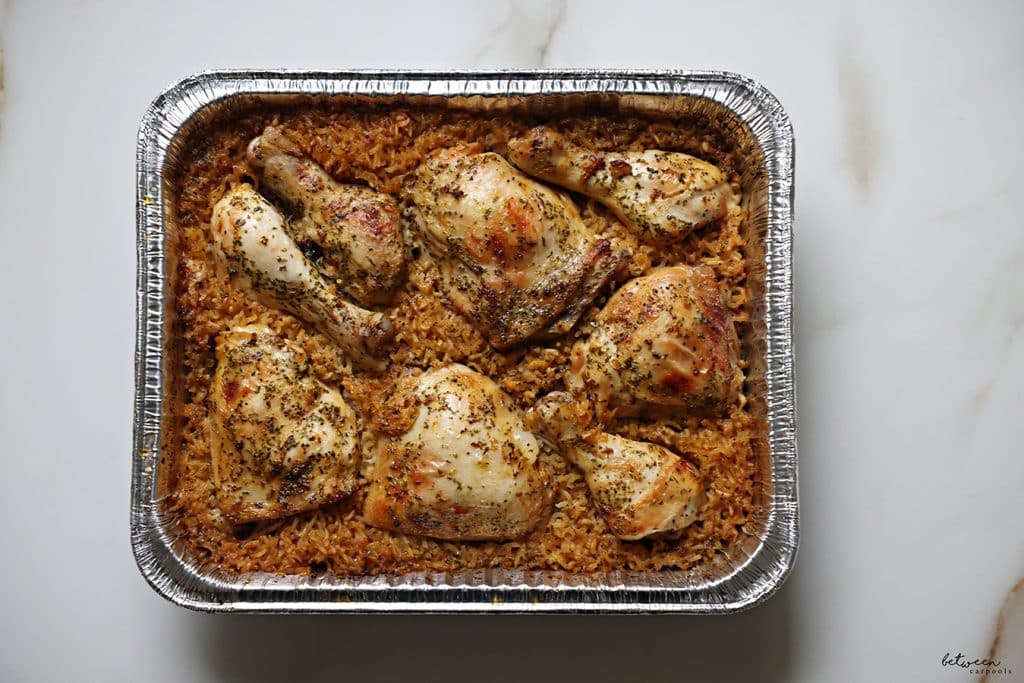 Baked chicken with rice in a 9x13 aluminum pan.
