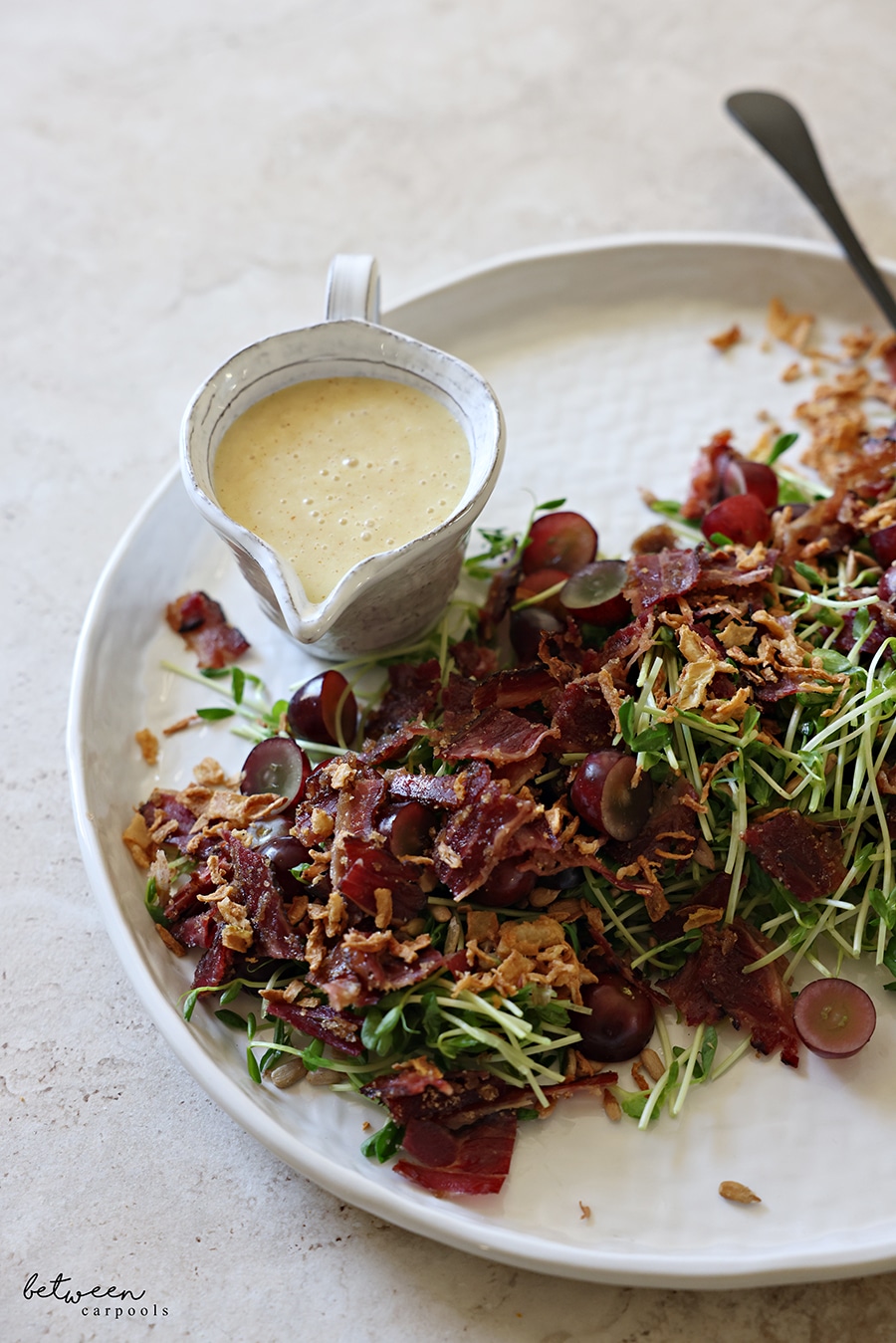 Pea Shoot Salad, plated, with a creamer of salad dressing.