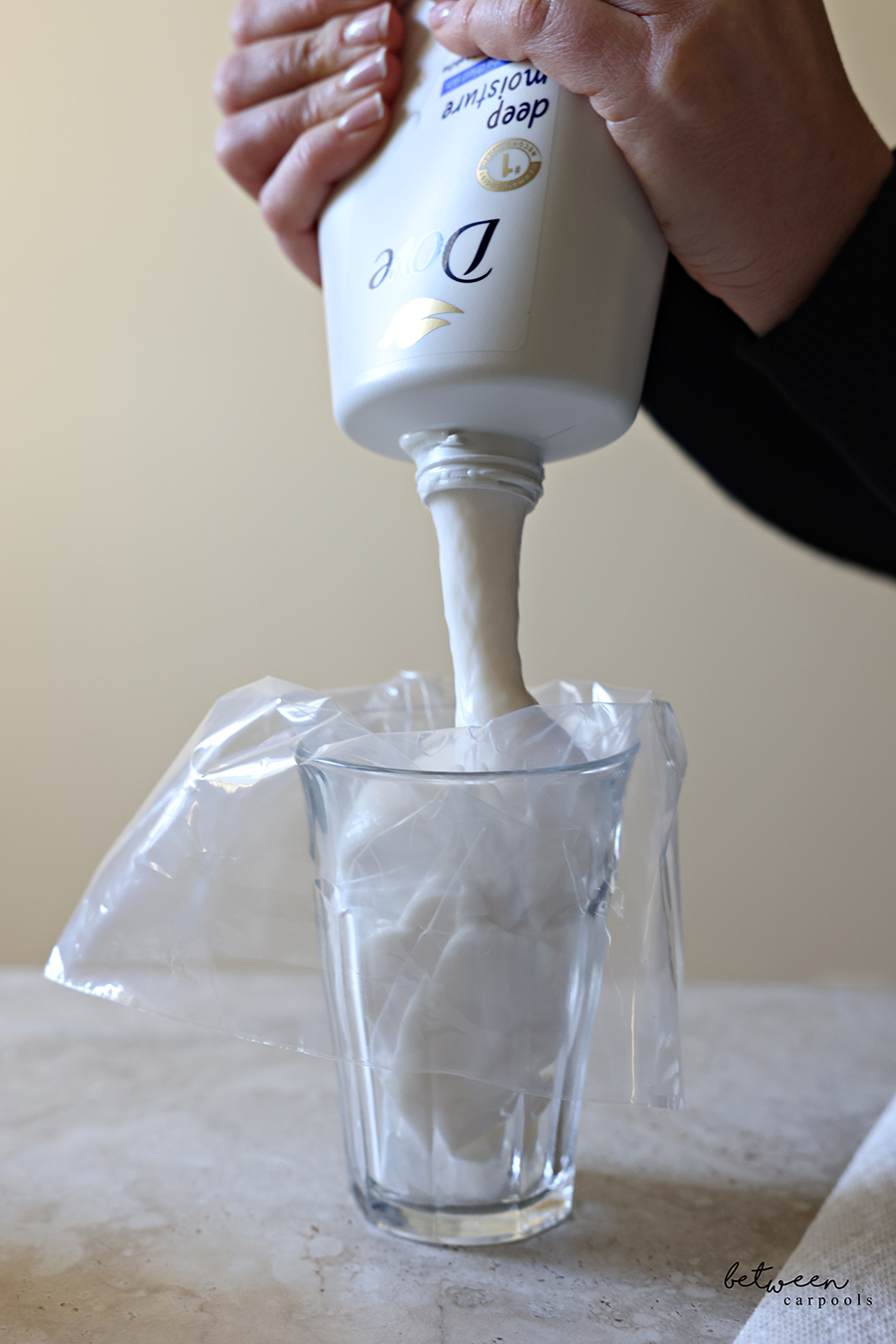 Pouring Dove body wash into a piping bag set in a glass cup.