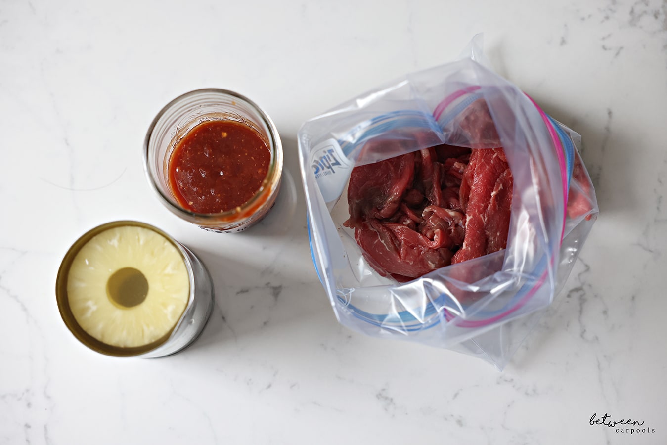 Canned pineapple, homemade bbq sauce in a glass mason jar, and a Ziploc bag with thinly sliced shoulder meat.