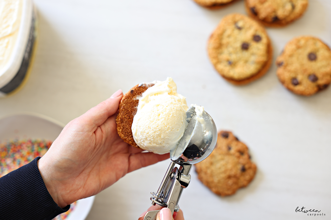 Adding a scoop of vanilla ice cream to the underside of one chocolate chip cookie.