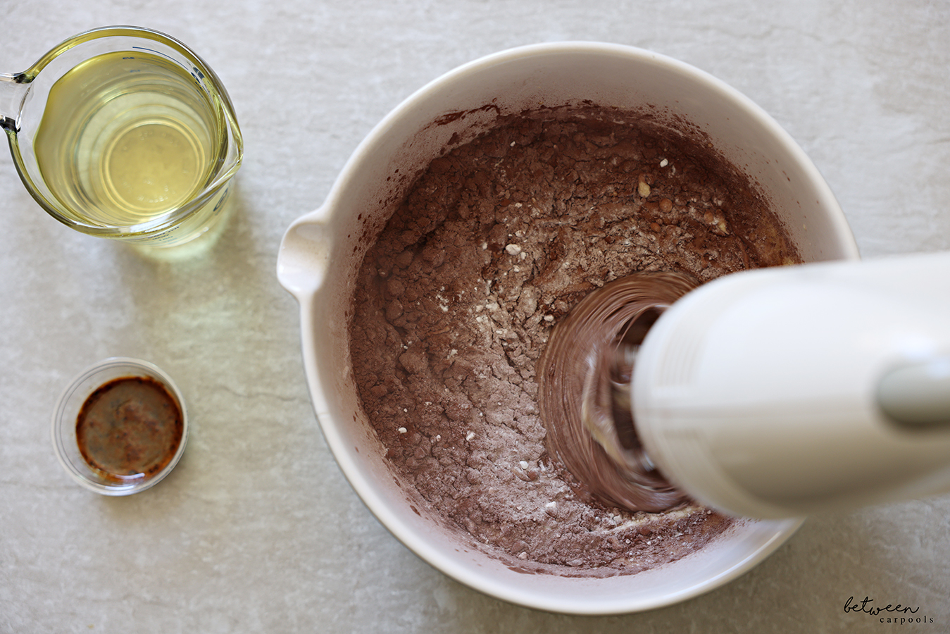Beating potato starch and cocoa with a creamy mixture of eggs and sugar in a mixing bowl with spout with a hand mixer.