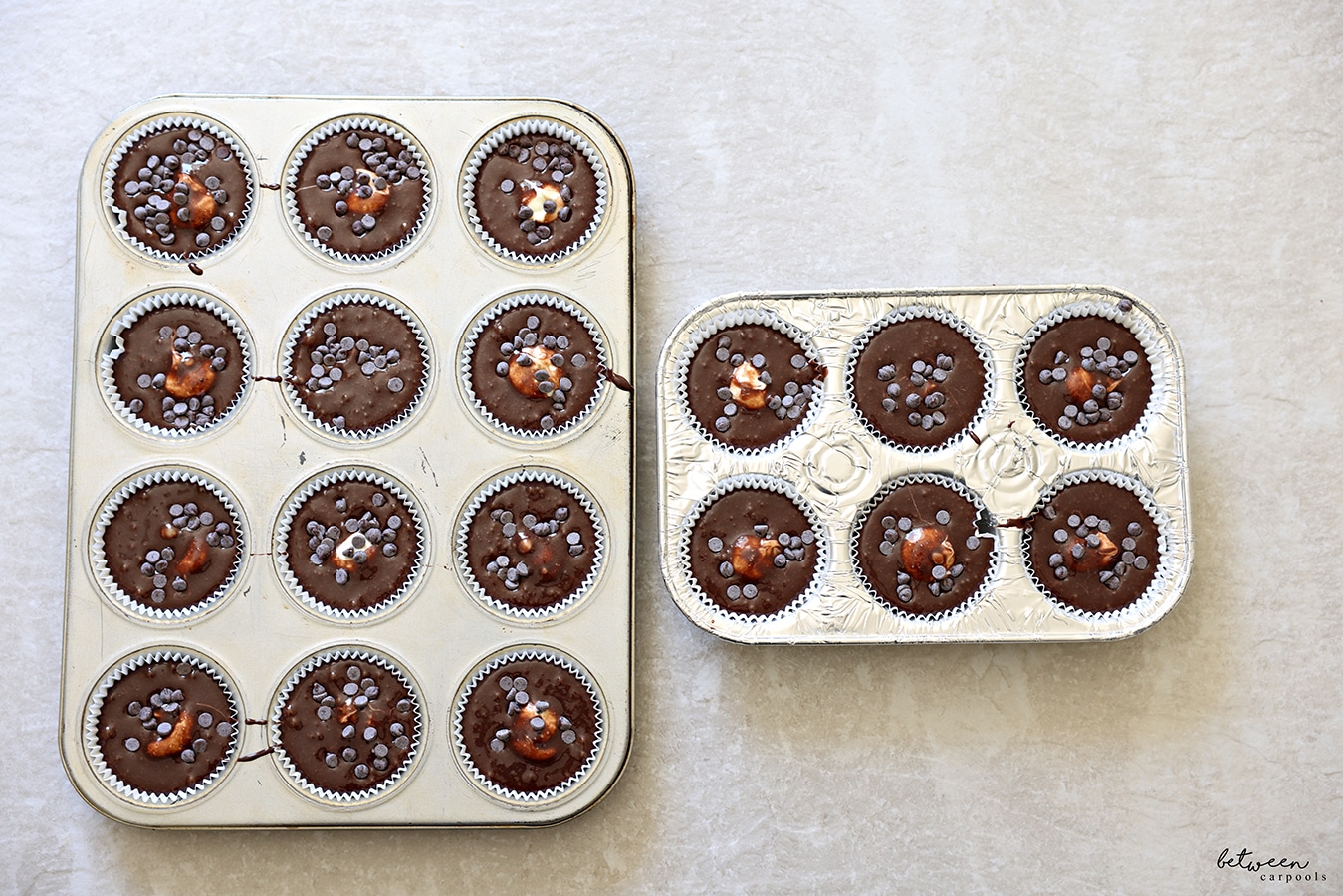 Muffin cups filled with chocolate batter and cheese filling, sprinkled with mini chocolate chips.