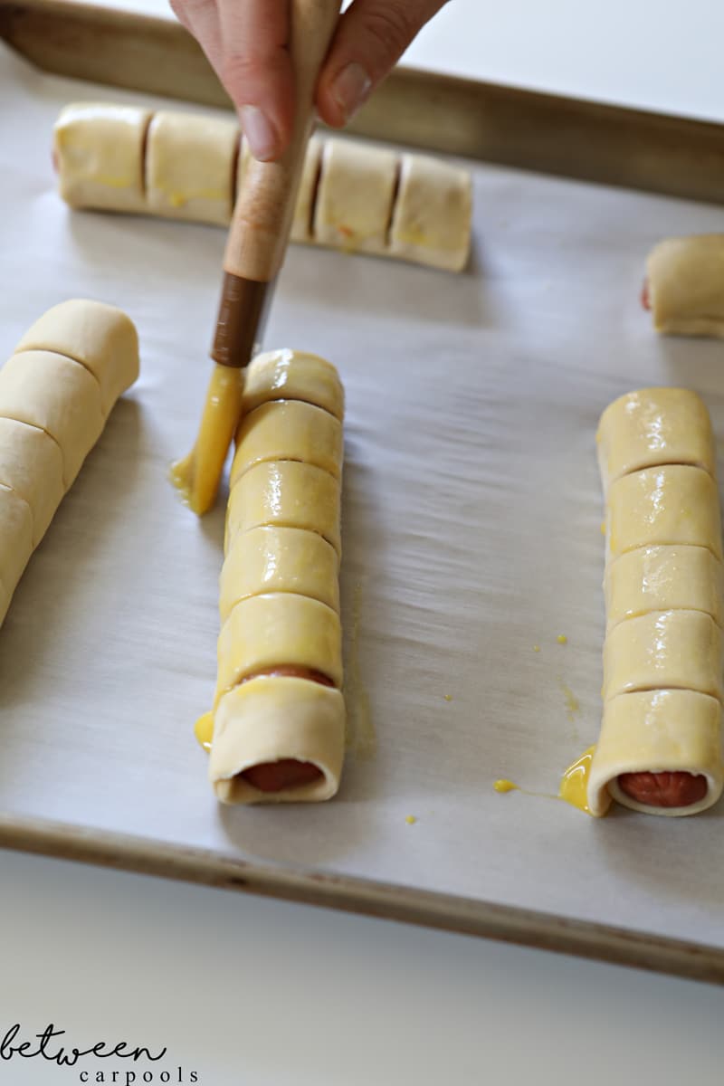 egging pull apart hot dogs on a parchment lined baking sheet ready to go into the oven