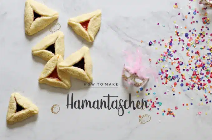 Baked hamantaschen on marble background. Mardi Gras mini mask and colorful paper confetti