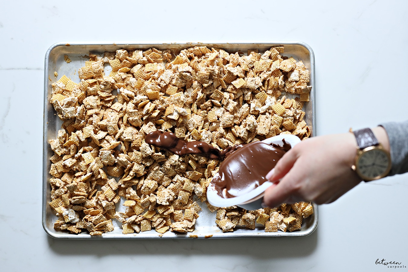 Pouring melted chocolate over Chex with lotus spread and marshmallow fluff.