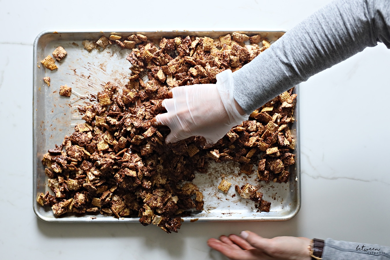 Mixing melted lotus spread, marshmallow fluff and chocolate with Chex to coat well.