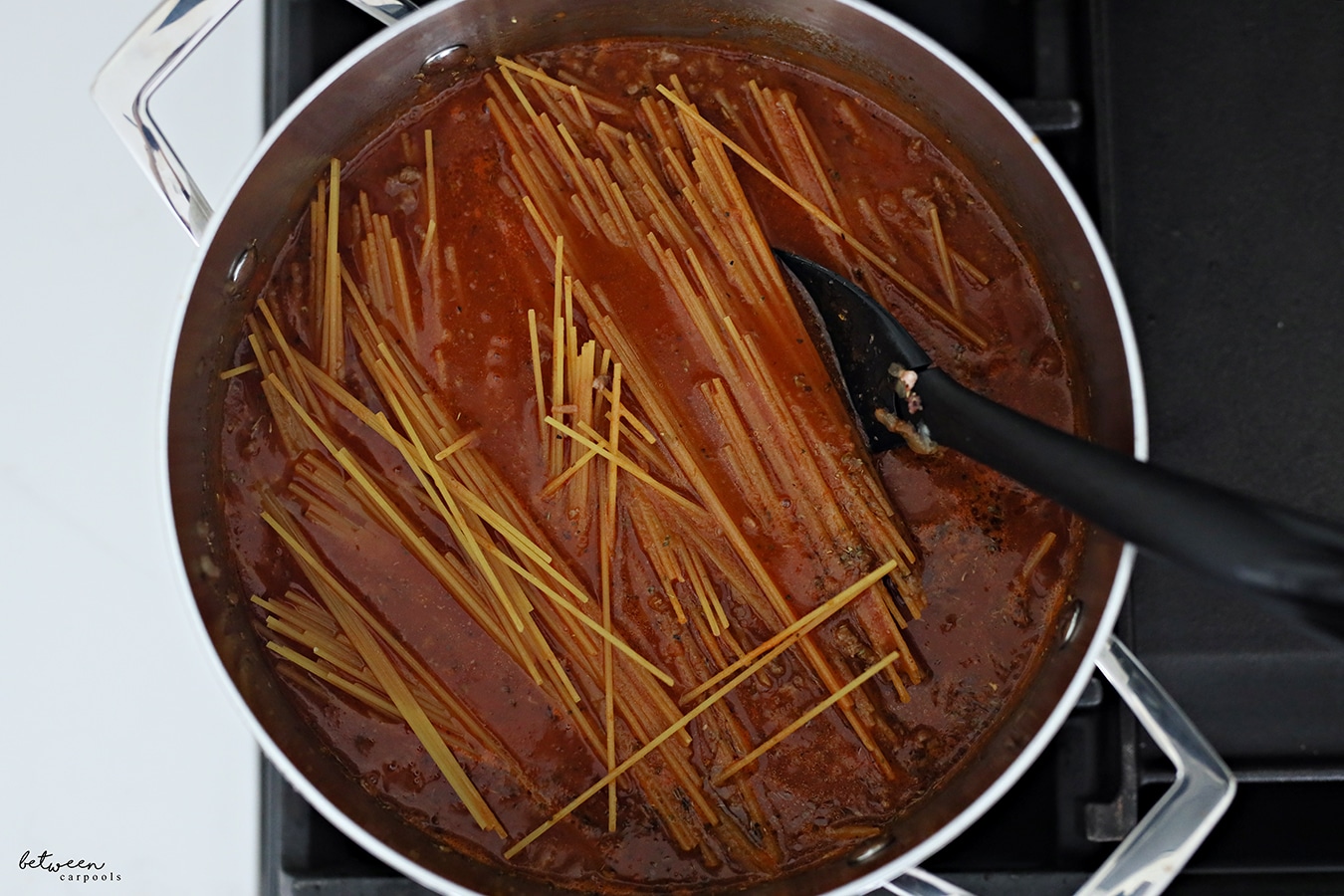 Spaghetti added to marinara sauce, Italian seasoning and water that has been brought to a boil for spaghetti and meat sauce in one pot.