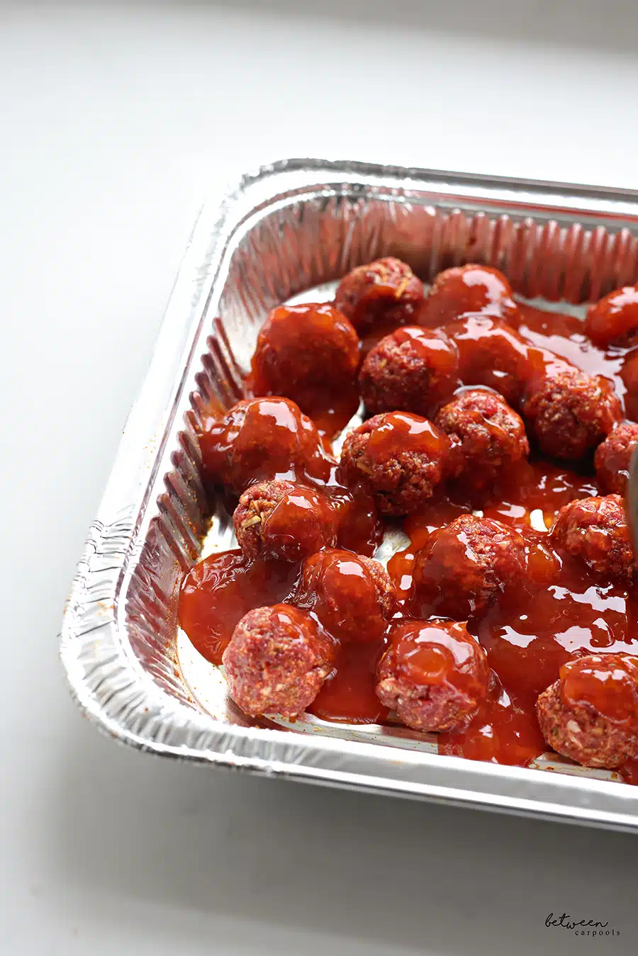 Raw meatballs and sauce in a 9x13 pan.