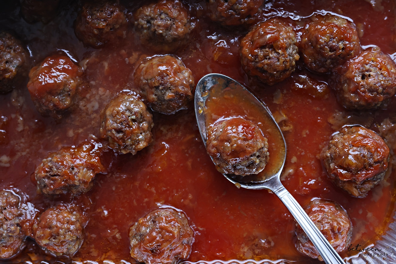 Baked meatballs in a 9x13 pan, with a spoon.