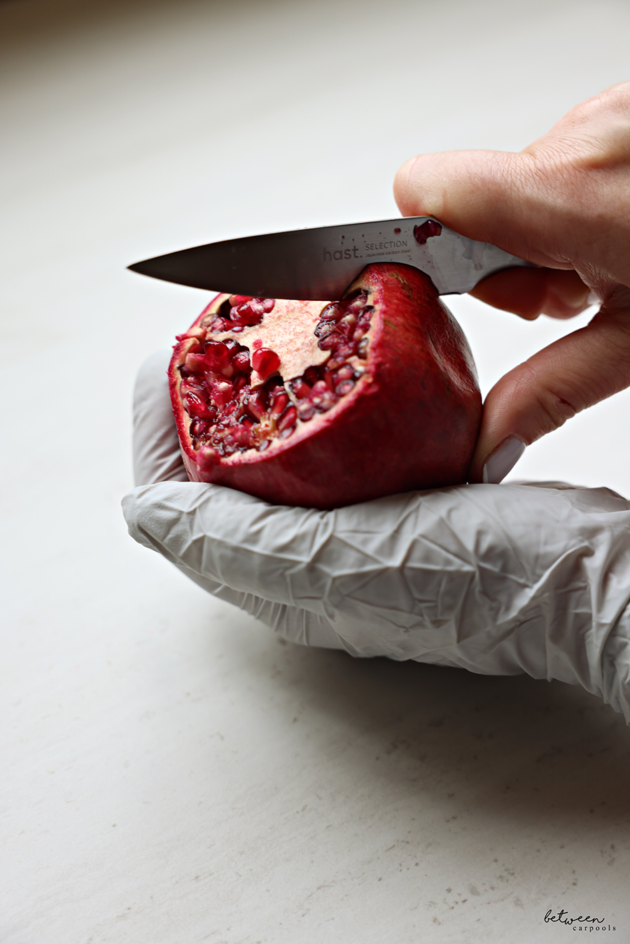 using hast utility knife to score a pomegranate in hand