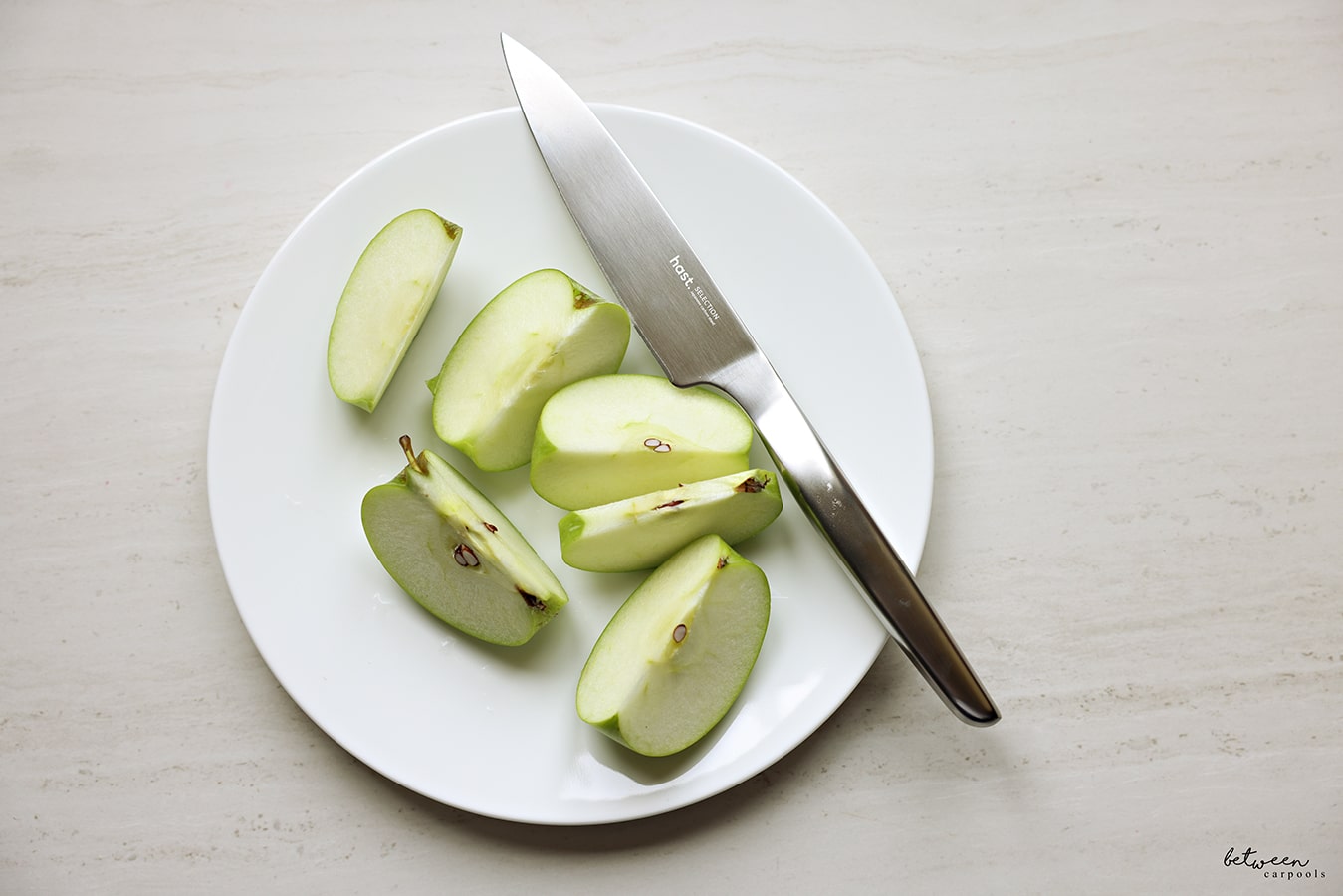 hast utility knife on a white plate with a sliced green apple