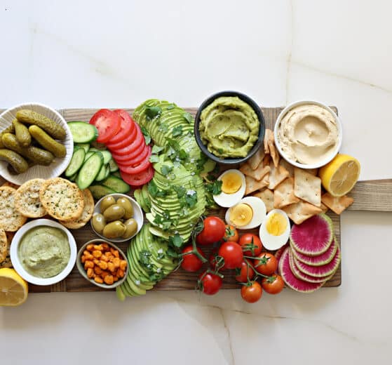 An assembled avocado board, finished with sea salt, and fresh herbs on top of the avocado.