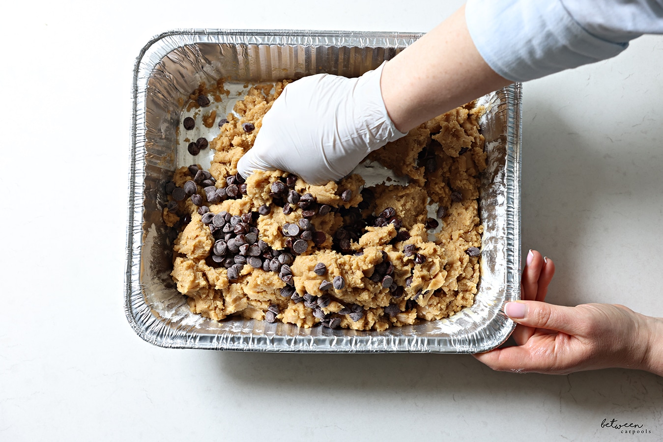 Combining cookie dough for Easy Oven S'mores Bars with a gloved hand.