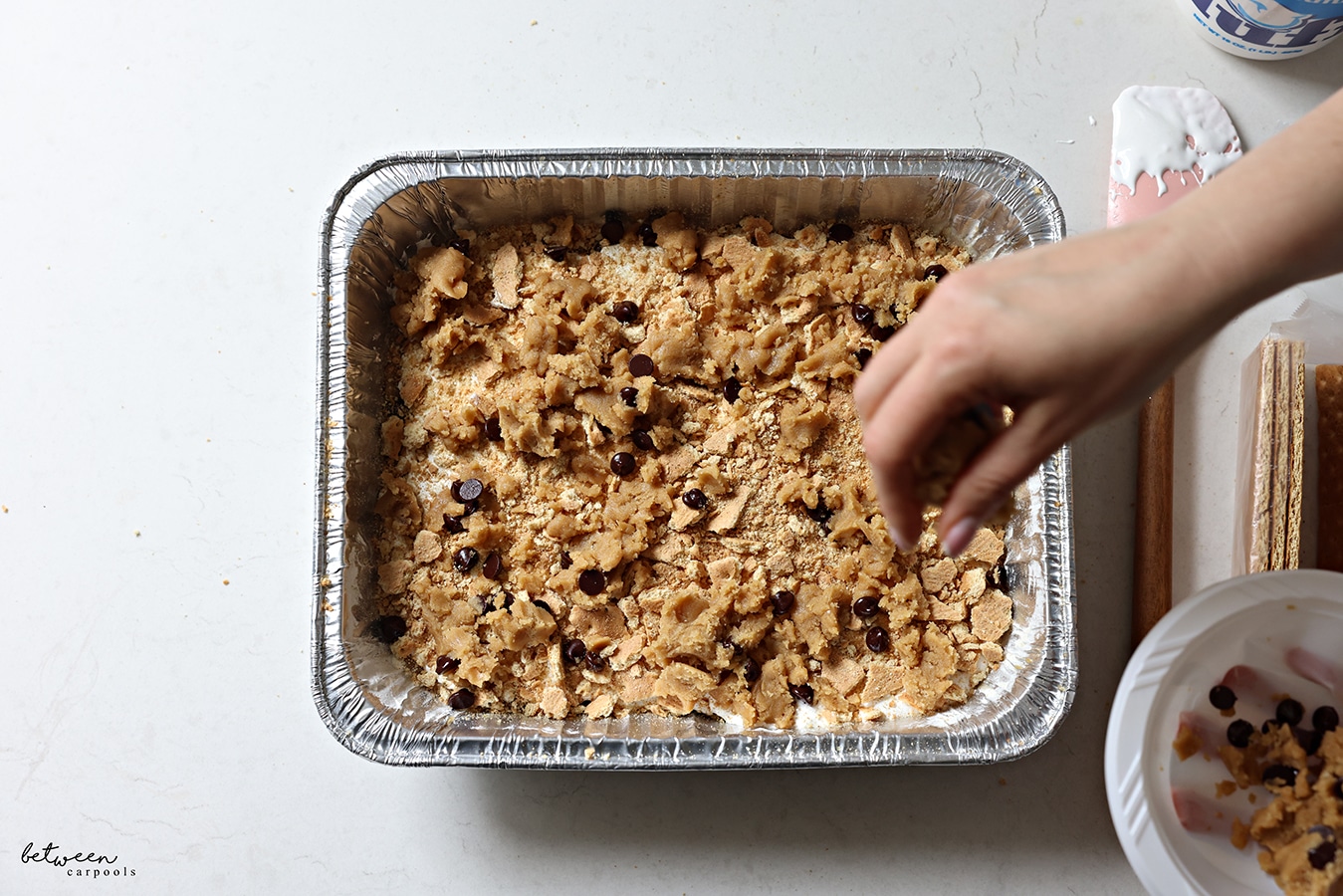 Topping with crumbled cookie dough for Easy Oven S'mores Bars.