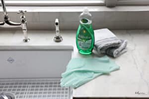 dish soap, dish cloths and gloves on the counter, at the edge of kitchen sink