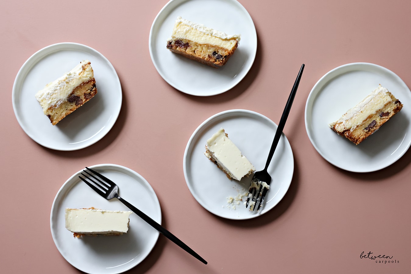 individual slices of cookie crust cheesecake on plates, with forks