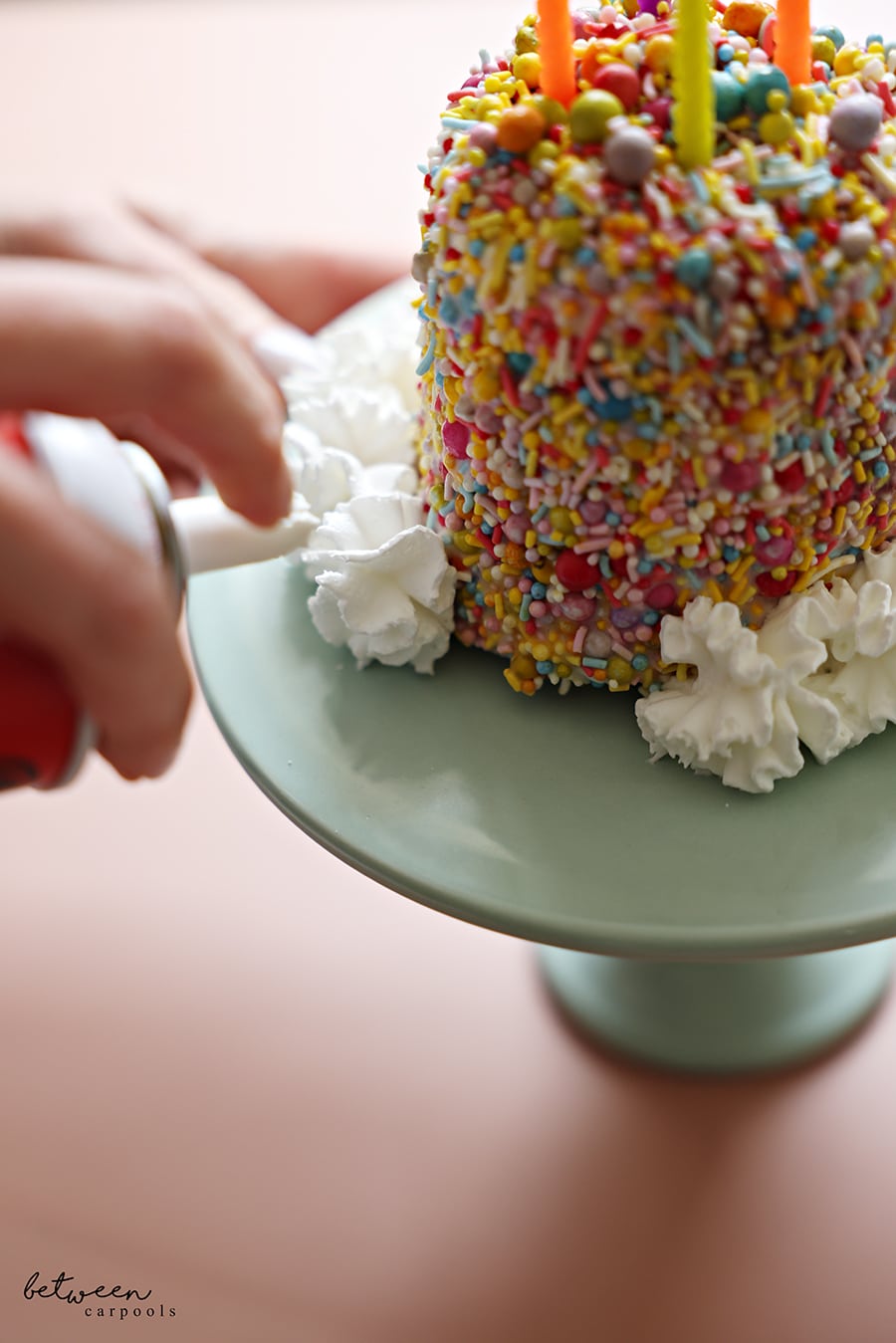 Piping whipped cream around the pint of ice cream cake. on a cake stand