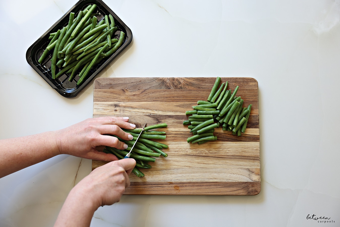 slicing green beans in half. on a cutting board