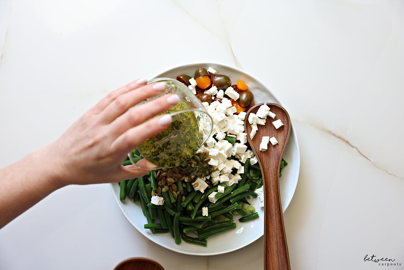 pouring dressing over green bean salad