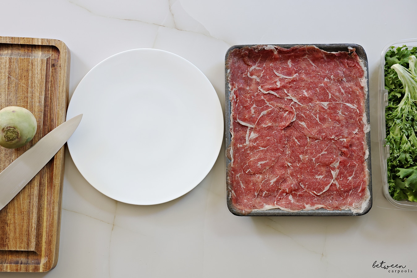 carpaccio meat and a white dinner plate, side by side